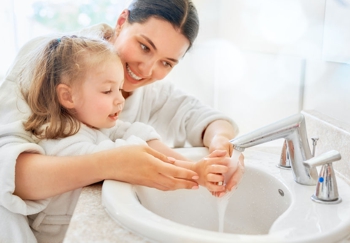 mom helping her daughter wash her hands to protect from coronavirus