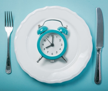 a clock on a plate intermittent fasting